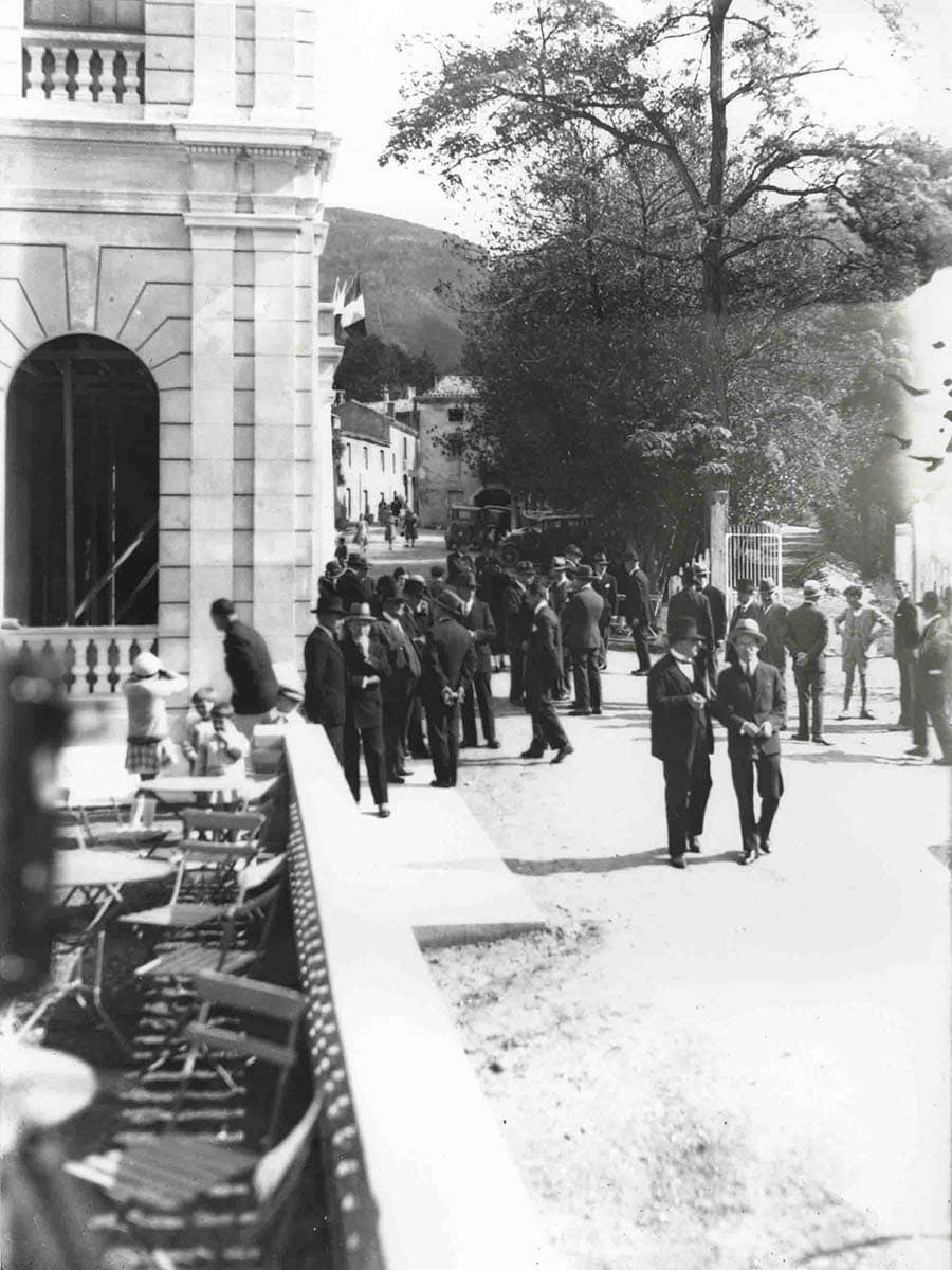 Photo d'archives de l'inauguration de l'Auberge des Dauphins en 1930 montrant une terrasse, le bâtiment et des personnes.